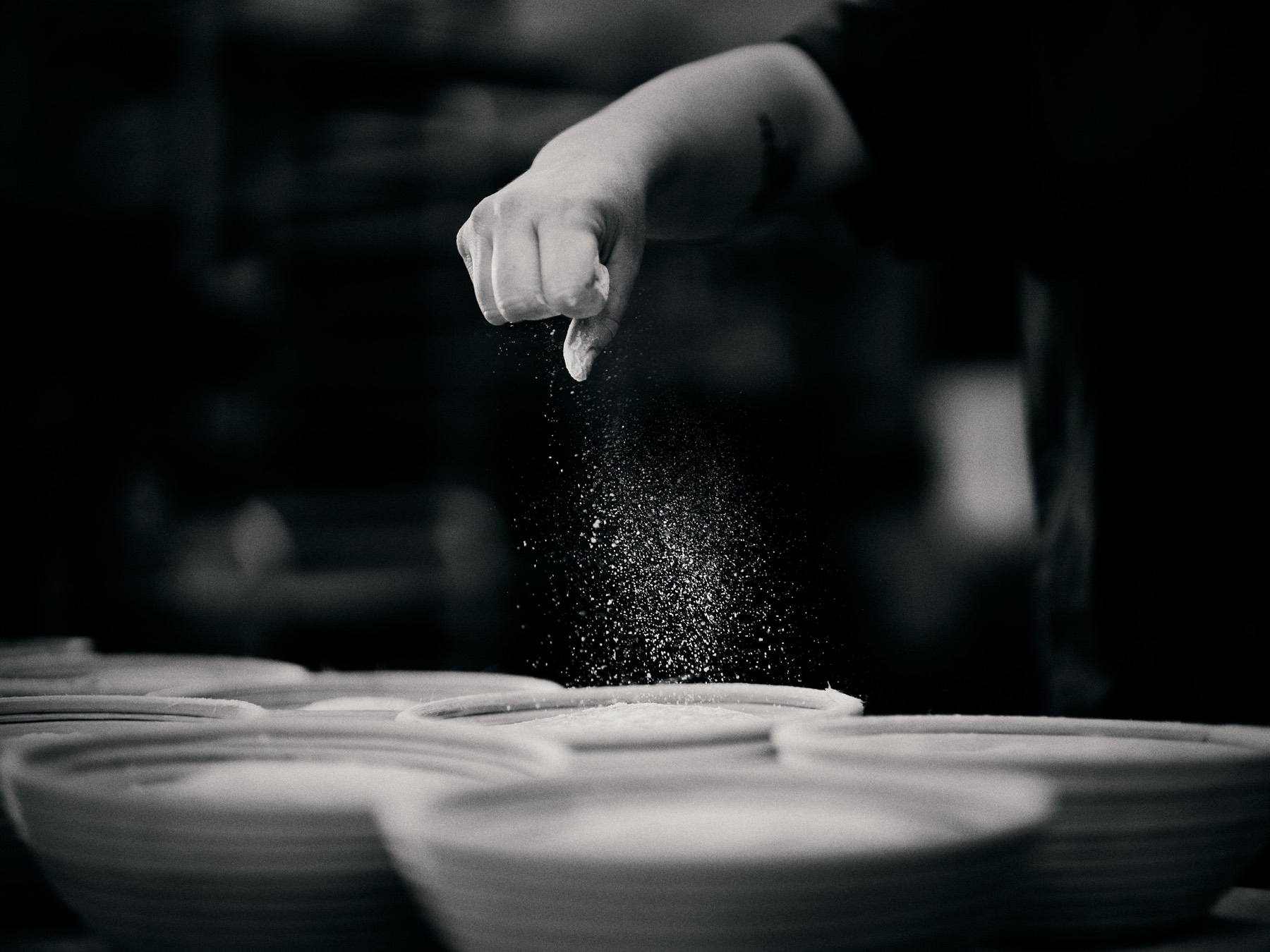 Baker dusting flour through the air